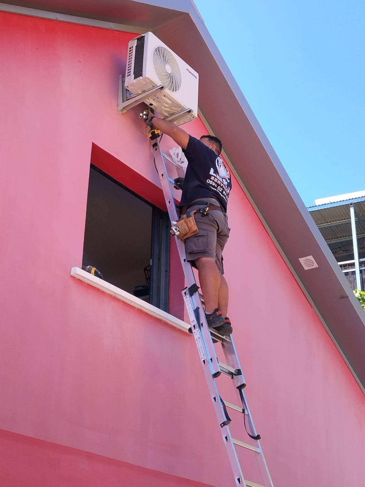 Technicien L2KJ installant une unité extérieure de climatisation à La Réunion