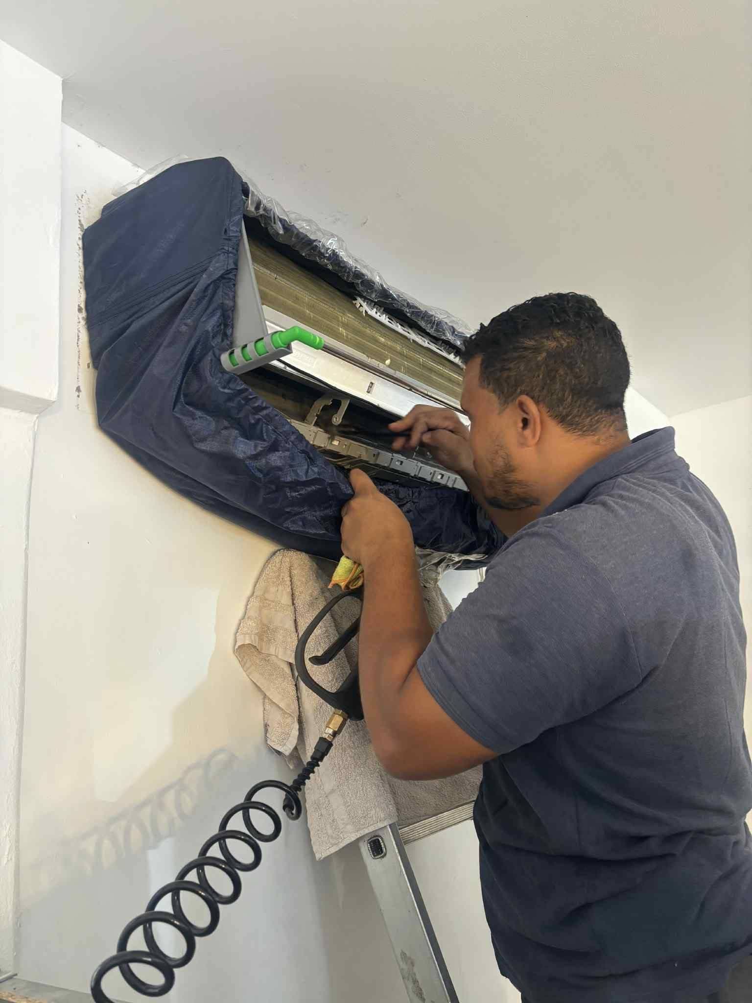 Technicien nettoyant une unité intérieure de climatisation ouverte